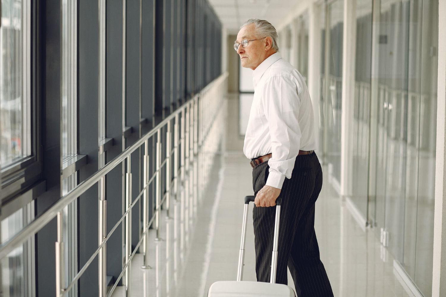 Older man walking through an airport terminal with luggage, illustrating confident travel with incontinence.
