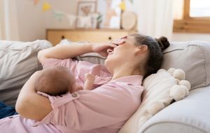 Distressed new mother resting with her baby during postpartum recovery