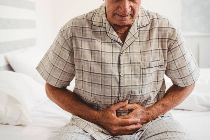 senior man with constipation holding stomach